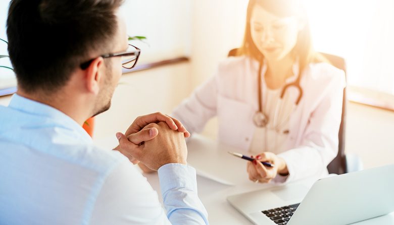 Portrait of female doctor sitting at desk with patient Portrait of female doctor sitting at desk with young patient while check up and write diagnosis.